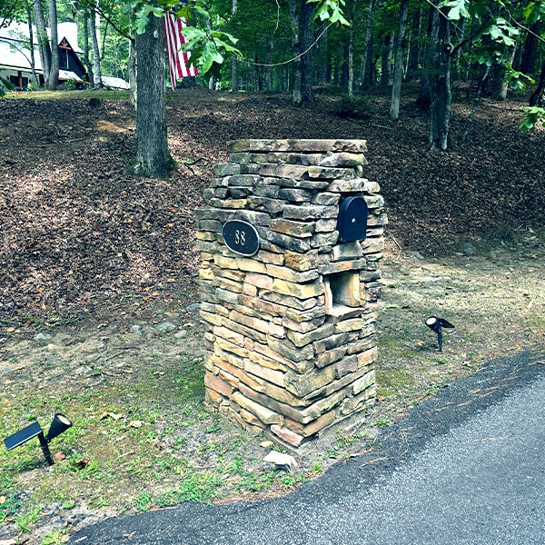 Stone mailbox column with moss before cleaning