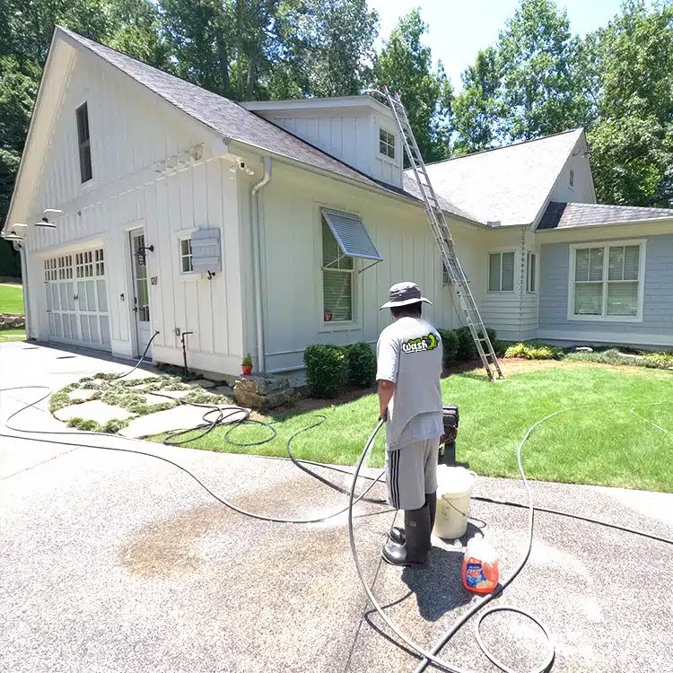 Cleaning Plus technician soft-washing a house exterior