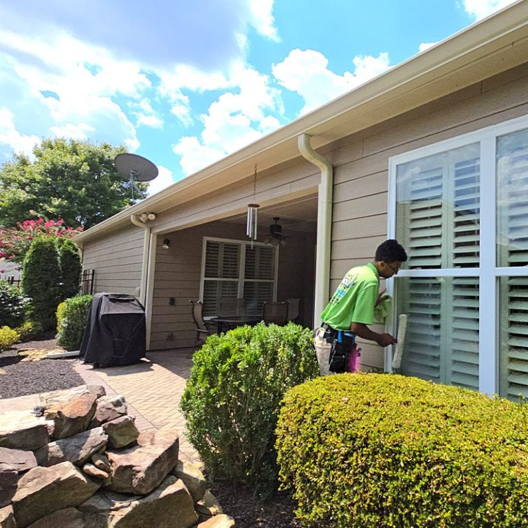Cleaning Plus technician cleaning windows on a home